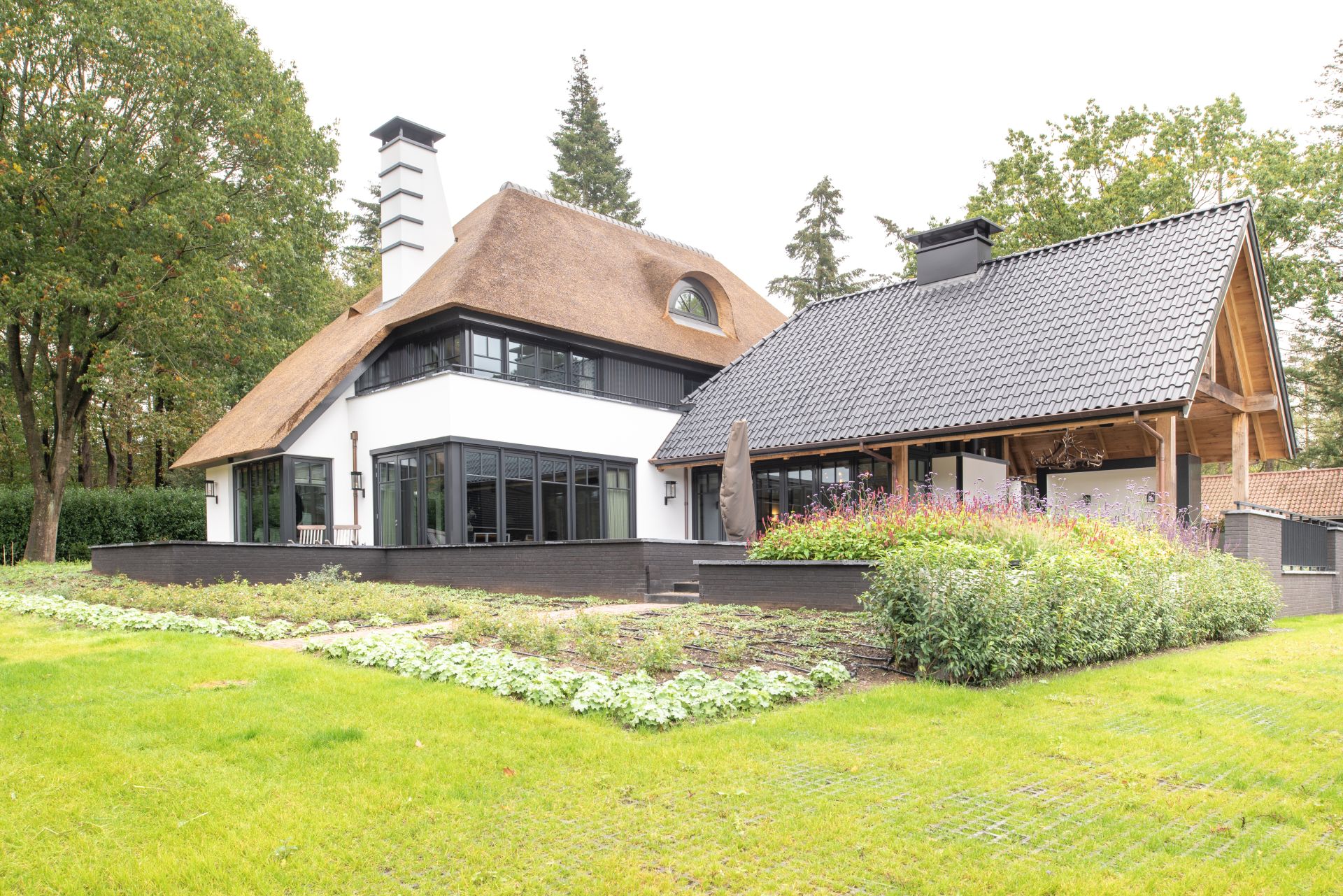 Zwarte kozijnen van hout, houten deuren en een trap met overstekende bloktreden geven deze woning karakter. Kozijnen op maat maken het geheel uniek.